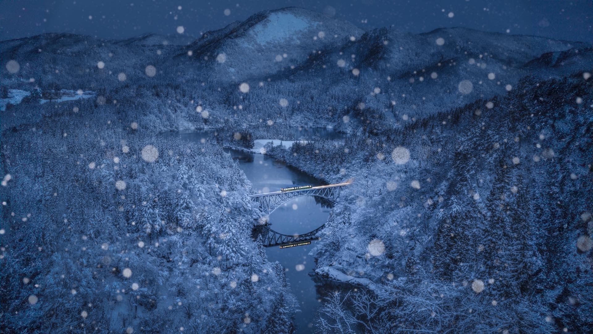 雪の降る夜、雪に覆われた山あいの川に鉄橋が架かる